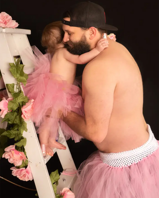 Dad and little daughter together wearing princess dresses for a photo